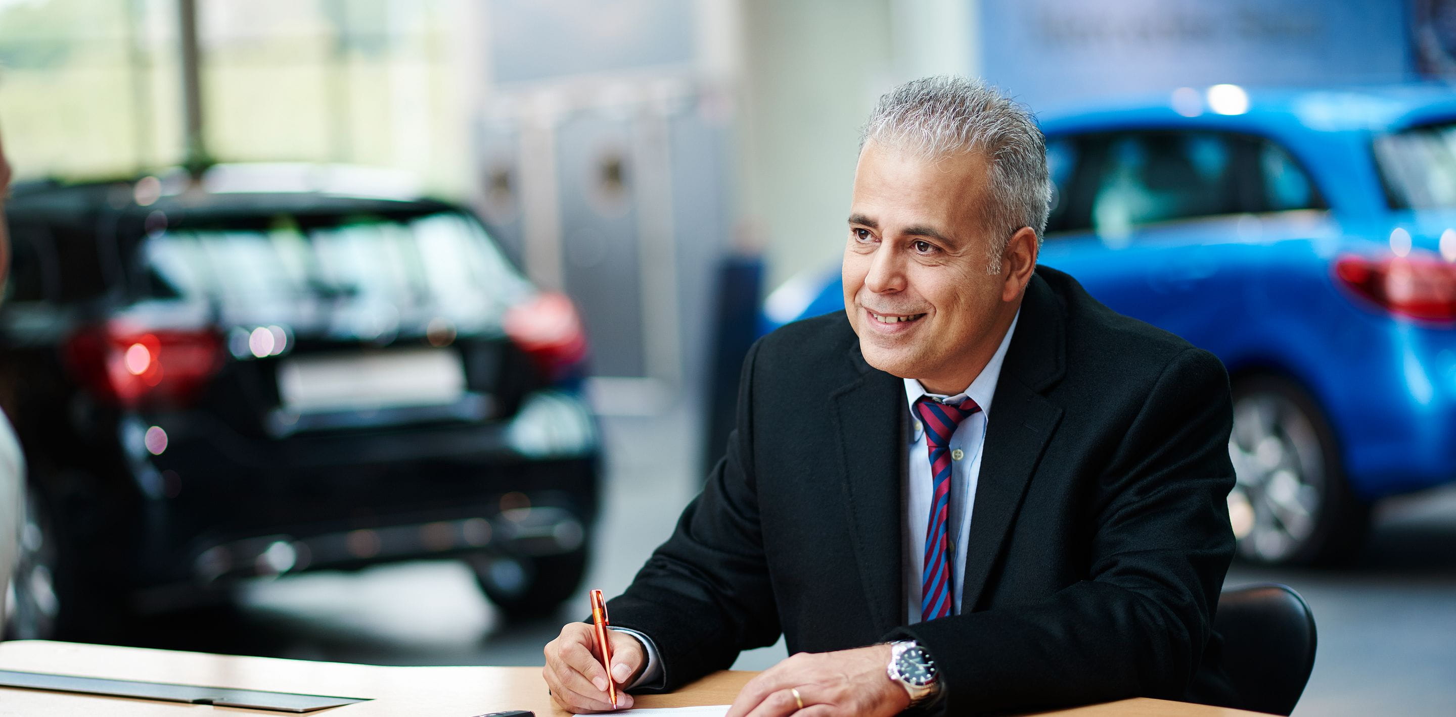 Dealership - man signing papers - cars in background