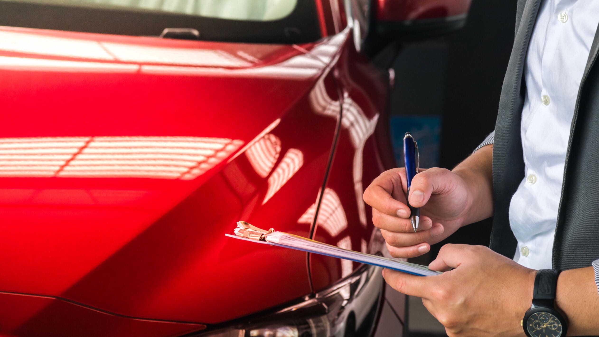 Writing contract next to red car